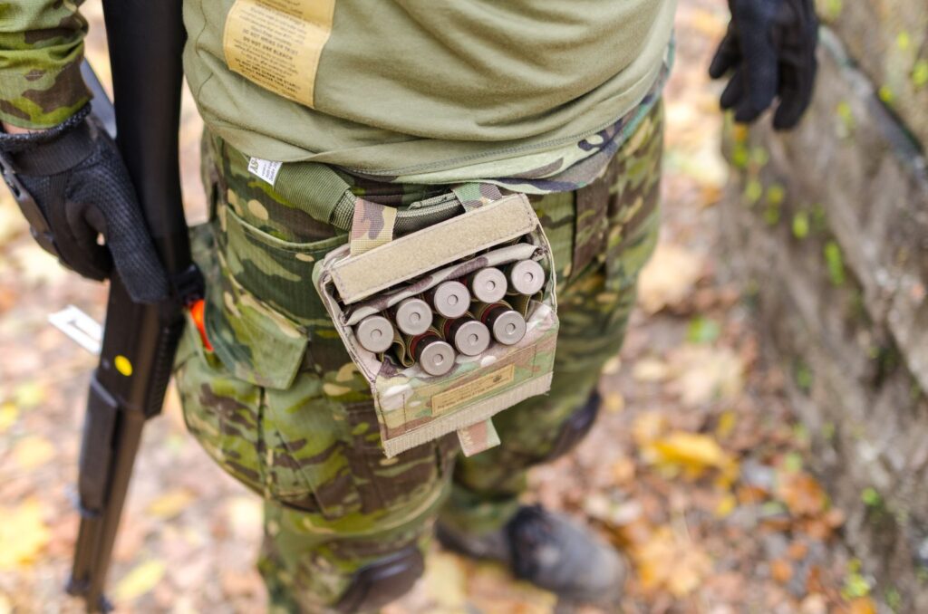 Hunter in camouflage carrying shotgun shells in a belt pouch on a fall day